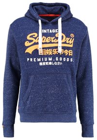 Sudadera azul marino de tela texturizada con cordones blancos, bolsillo canguro frontal y texto gráfico naranja en el pecho.
