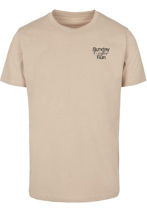 Camiseta de algodón color beige con mangas cortas y cuello redondo. Presenta un diseño de texto negro "Sunday Coffee Run" en el pecho. Textura suave.