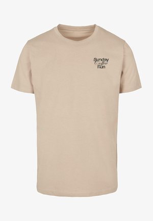 Béžové bavlněné tričko s krátkým rukávem a kulatým výstřihem. Na hrudi je černý textový design "Nedělní kávový výlet". Hladká textura.