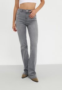 Harmaat farkut, joissa on levenevät lahkeet, keski-korkea vyötärö, viisi taskua ja yksittäinen etunappikiinnitys. Silkkinen pinta ja vaaleanpesu viimeistely.