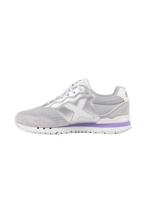 Zapatilla gris y plateada con logo blanco "X", franja lavanda en la suela, diseño con cordones y materiales texturizados mostrados de perfil.