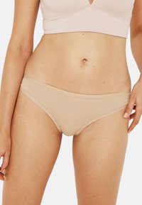 Sous-vêtements de style bikini nudes en tissu lisse, avec une coupe basse, des bords sans couture et une taille douce pour plus de confort.