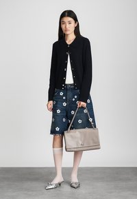 Czarny prążkowany kardigan z kołnierzykiem, biała koszulka, kwieciste dżinsowe szorty, szara skórzana torebka i metaliczne srebrne buty z noskami.