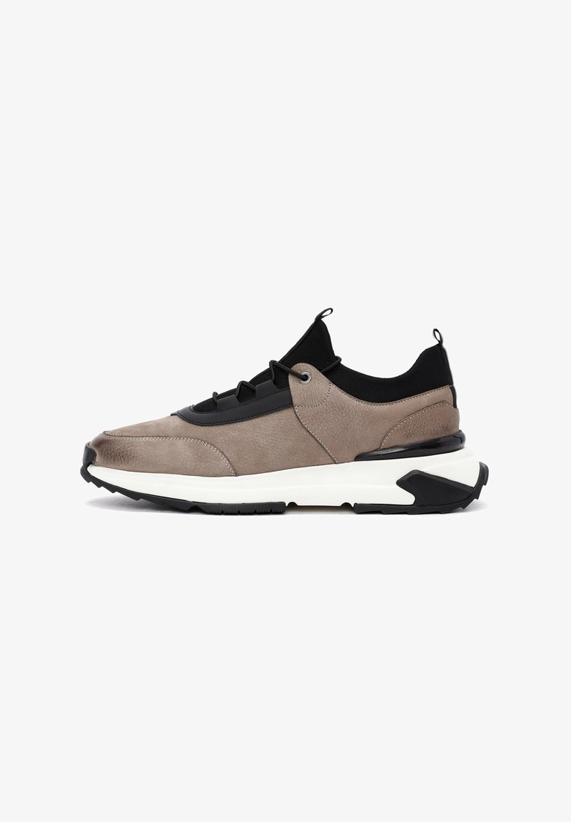 Sneaker mit einem Obermaterial aus beigem Leder, schwarzen Akzenten, runder Zehenform und dicker weißer Mittelsohle. Verfügt über elastische Schnürsenkel und Zuglaschen.