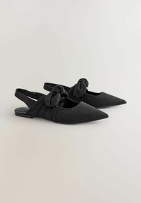 Bailarinas negras tipo slingback de ante, con punta afilada, detalle de lazo anudado y tacón plano con un acabado suave.