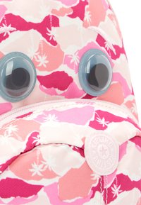 Kipling rygsæk med et pink og hvidt mønster af palmeblade, to store plastiske øjne og et rundt logo-patch. Glat stofstruktur.