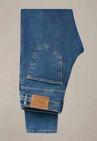 Niebieskie dżinsy z podwiniętą nogawką, ukazujące tylną kieszeń, skórzaną naszywkę z marką oraz subtelne detale szycia, na neutralnym tle.