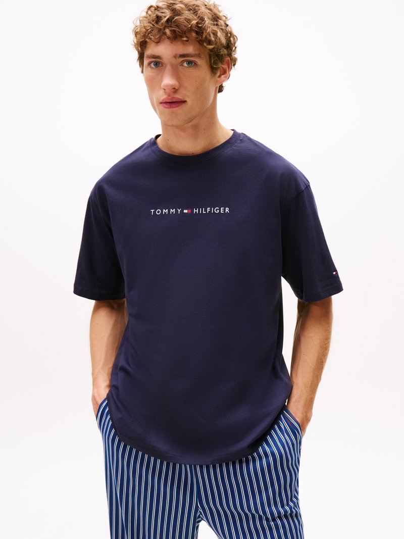 T-shirt en coton bleu marine à manches courtes et col rond. Arbore le logo "TOMMY HILFIGER" en blanc, souligné par un rectangle rouge et bleu.