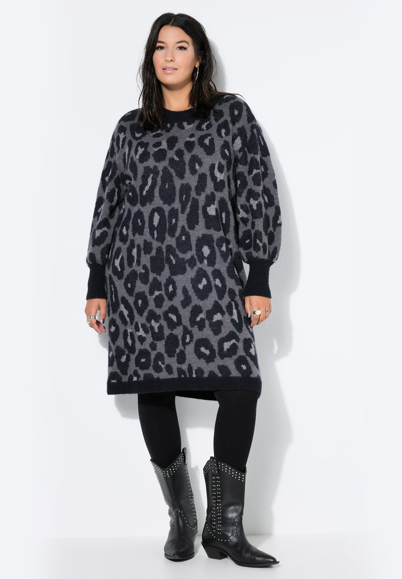 Grijze sweaterdress met luipaardprint, losvallend en met pofmouwen, gecombineerd met zwarte leggings en gestudeerde zwarte cowboylaarzen.