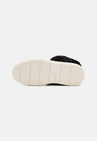 Svarta pälsskor med en texturerad vit gummisula som har ett hjärtmönster och "LOVE MOSCHINO"-logotypen präglad. Platt och rund form.