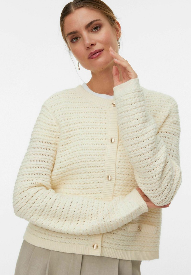Cardigan in maglia crema con righe orizzontali, colletto e polsini a coste e grandi bottoni frontali. Texture morbida con dettagli sottili.