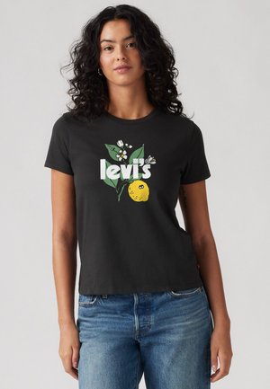 T-shirt en coton noir arborant un motif graphique de citron jaune et de fleurs, avec le texte "levi's" en blanc. Manches courtes, col rond.