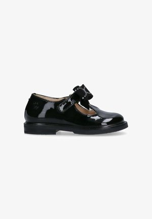 Scarpa in pelle nera lucida con punta rotonda, tacco basso e un fiocco decorativo sulla cinghia. Texture liscia, lucentezza sottile e dettagli curati.
