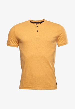 T-shirt jaune à manches courtes avec un col rond, doté d'une patte de boutonnage à trois boutons et d'un tissu doux et texturé.