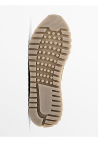 Sole of a shoe, beige rubber with textured patterns, including ridges and circular bumps, and a brand name embossed near the heel.