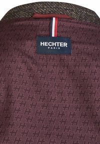 Burgundy fabric featuring a repeated geometric pattern and a textured collar. Includes a "HECHTER PARIS" label with three color stripes.