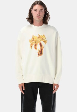 Felpa crema con una grande grafica infuocata in tonalità di giallo e arancione. Presenta una vestibilità rilassata e polsini a costine.