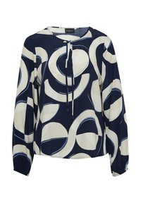 Blouse marine avec de grands motifs circulaires crème et bleu. Présente un col rond, un lien à tirage et de longues manches avec des poignets élastiques.