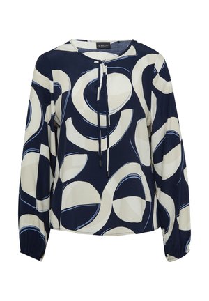 Blouse marine avec de grands motifs circulaires crème et bleu. Présente un col rond, un lien à tirage et de longues manches avec des poignets élastiques.