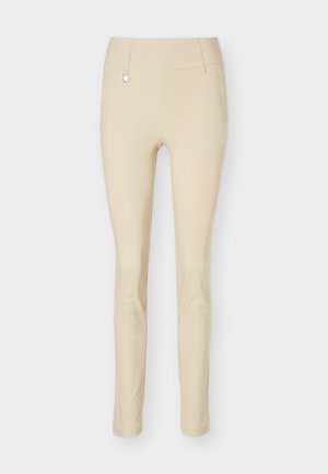 Μπεζ παντελόνι με στενή γραμμή, με μέση μεσαίου ύψους και μικρή διακοσμητική λεπτομέρεια δαχτυλιδιού κοντά στη μέση σε απλό φόντο.