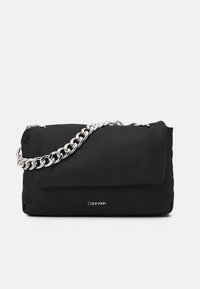 Sac à main rectangulaire noir avec une bandoulière en chaîne argentée et un petit logo Calvin Klein sur le devant, le tout sur fond blanc.