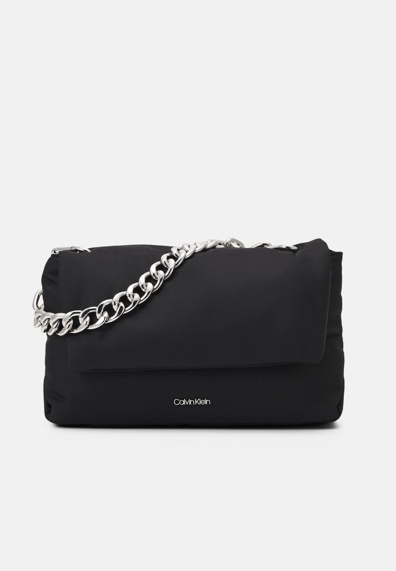 Sac à main rectangulaire noir avec une bandoulière en chaîne argentée et un petit logo Calvin Klein sur le devant, le tout sur fond blanc.