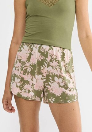 Zielone krótkie spodenki w kwiatowy wzór na różowym tle, wykonane z miękkiego materiału, z elastycznym pasem i luźnym krojem. Odpowiednie do noszenia na co dzień.
