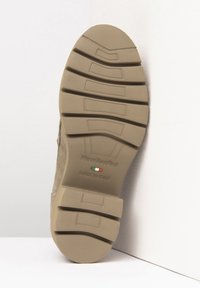Semelle de chaussure en caoutchouc beige avec de profondes rainures et motifs texturés, arborant les étiquettes "NeroGiardini" et "FABRIQUÉ EN ITALIE" avec les couleurs du drapeau italien.