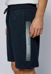 Námořnické modré sportovní šortky z bavlněné směsi, s bočn�ím pruhem s tečkovaným vzorem a logem v bílé a tyrkysové barvě.