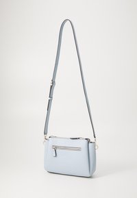 Sac bandoulière bleu clair en matériau synthétique texturé, avec une poche zippée à l'avant et une sangle réglable avec des détails en métal argenté.