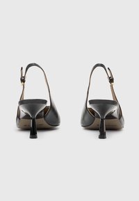 Črne usnjene slingback pete s koničastim nosom, ki imajo tanek, sijoč peto in nastavljiv zadrgo na gležnju. Gladka tekstura, minimalne podrobnosti.