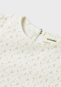Abito in cotone bianco con motivo floreale in rosa e verde, caratterizzato da un collo rotondo e chiusura con bottoni sul retro del marchio Lil'Atelier.