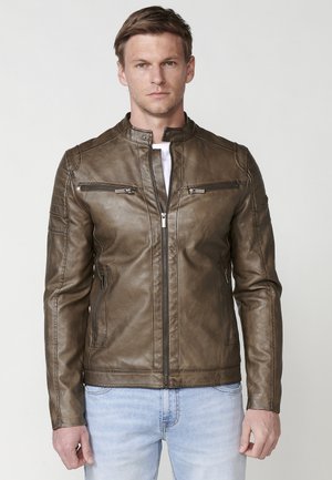 Chaqueta de cuero marrón con un cuello alto acanalado, dos bolsillos en el pecho con cremallera y un diseño ajustado. Textura suave con un acabado elegante.