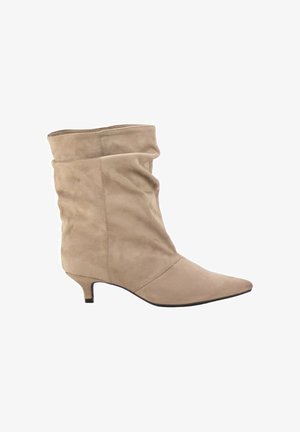 Bota beige de ante hasta la mitad de la pantorrilla con punta puntiaguda y tacón bajo tipo gatito, con un diseño superior ligeramente caído.