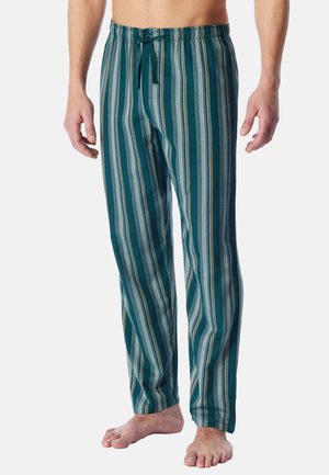 Man wearing teal, gray, and mustard vertical striped pajama pants with a drawstring waistband, standing barefoot against a plain background.