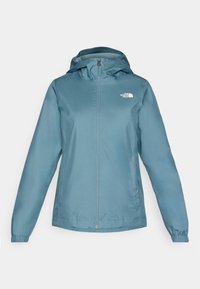 Ljusblå vattentät jacka av slätt material, med dragkedja fram, justerbar huva och elastiska ärmmuddar. Logotyp på vänster bröst.