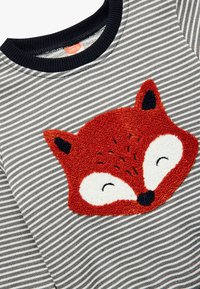 Sudadera de rayas en gris y blanco con un apliqué texturizado de la cara de un zorro naranja en la parte frontal, con acentos en negro en las orejas y un cuello acanalado.
