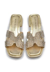 Gouden slippers met een platte zool, voorzien van een grote strik versierd met rhinestones en een gladde metallic afwerking. Merknaam op de inlegzool.