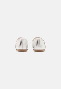 Pantofi plat metalici argintii cu o textură netedă, spate rotunjit și o talpă joasă, crem. Design simplu, fără accesorii sau detalii suplimentare.