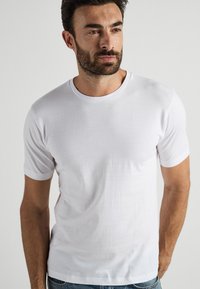 Vit bomullströja med korta ärmar, rund hals och slät yta. Inga mönster eller detaljer synliga. Avslappnad passform.