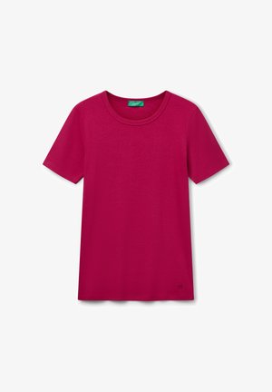 T-shirt a maniche corte girocollo in tinta unita rosa scuro, con un piccolo logo vicino all'orlo inferiore e un'etichetta del marchio verde all'interno del colletto.