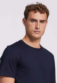 Marineblauwe katoenen t-shirt met een ronde halslijn, korte mouwen en een zachte textuur. Eenvoudig, effen kleur zonder zichtbare patronen of accenten.