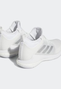 Vita atletiska skor med mesh-ovandelar, dämpade sulor och en strukturerad design. Har tre subtila grå ränder och en hälla på bakfoten.