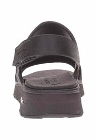 Sandalias negras con una suela gruesa y texturizada, correa ajustable y parte trasera abierta; fabricadas con material sintético diseñado para la comodidad.