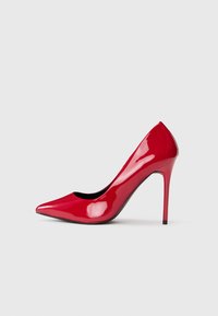 Blizgus raudonas aukštakulnis batelis su smailiu priekiu ir stiletto kulnu, rodomas šoniniame profilyje ant vientiso šviesaus fono.