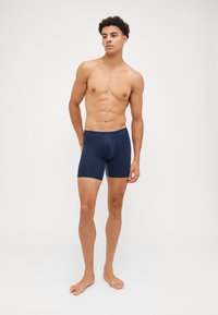 Navy blue athletic boxer briefs with a fitted design, elastic waistband, and smooth texture, featuring a mid-thigh length cut.