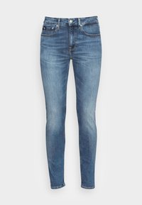 Jeans ajustados en denim azul claro, con una cintura de media altura, diseño clásico de cinco bolsillos y un ligero desgastado, con cierre de botón metálico y cremallera.