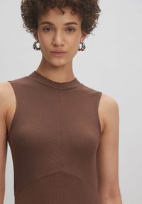 Braunes, geripptes, ärmelloses Oberteil mit hohem Kragen, das ein tailliertes Design und subtile Nahtdetails aufweist. Glatte Textur mit sportlichem Aussehen.