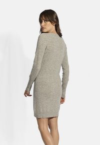 Abito grigio a maglia con maniche lunghe, orlo e polsini a coste. Tessuto morbido e forma aderente, che arriva a metà coscia in lunghezza.