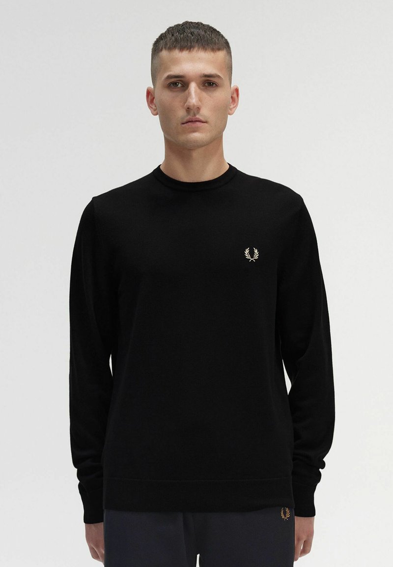 Schwarzer Langarmpullover aus weichem Stoff, mit Rundhalsausschnitt und einem kleinen goldenen gestickten Lorbeerlogo auf der linken Brust.
